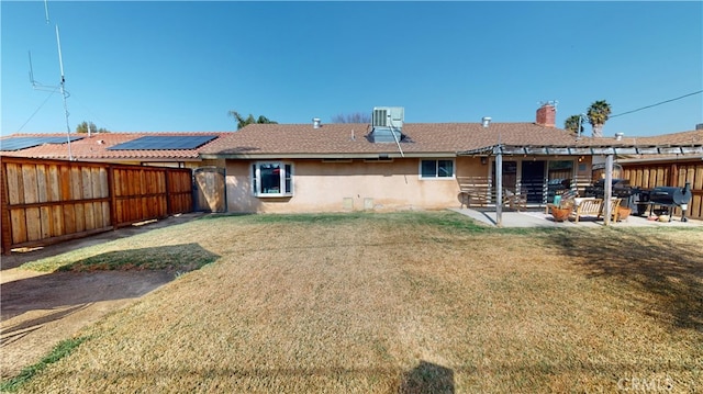 back of property with a yard, central air condition unit, a patio, and solar panels