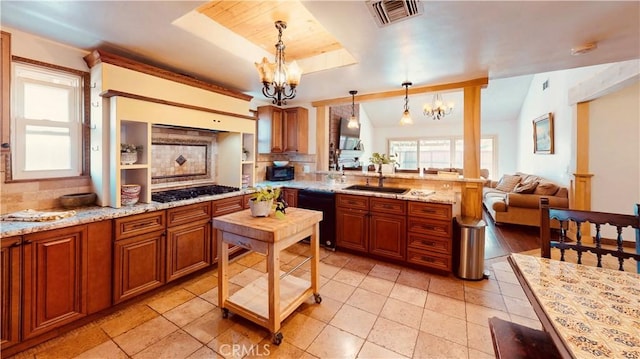 kitchen featuring pendant lighting, stainless steel gas stovetop, dishwasher, sink, and a chandelier