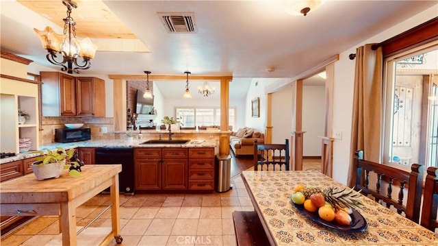 kitchen with sink, light stone counters, decorative light fixtures, a chandelier, and black appliances