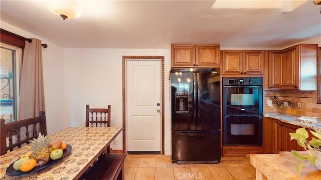 kitchen with light tile patterned floors, decorative backsplash, light stone counters, and black appliances