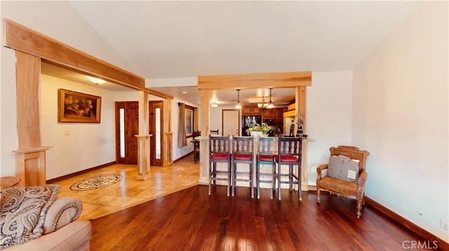 interior space featuring vaulted ceiling, wood-type flooring, and black fridge