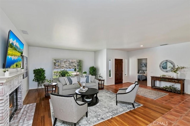 living room featuring a brick fireplace and hardwood / wood-style flooring