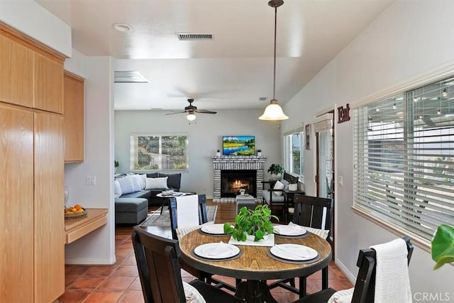 dining area featuring a fireplace, light tile patterned floors, a wealth of natural light, and ceiling fan