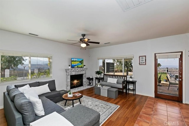 living room with hardwood / wood-style flooring, a brick fireplace, and ceiling fan