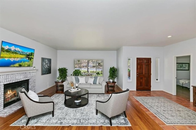 living room featuring a brick fireplace and hardwood / wood-style floors