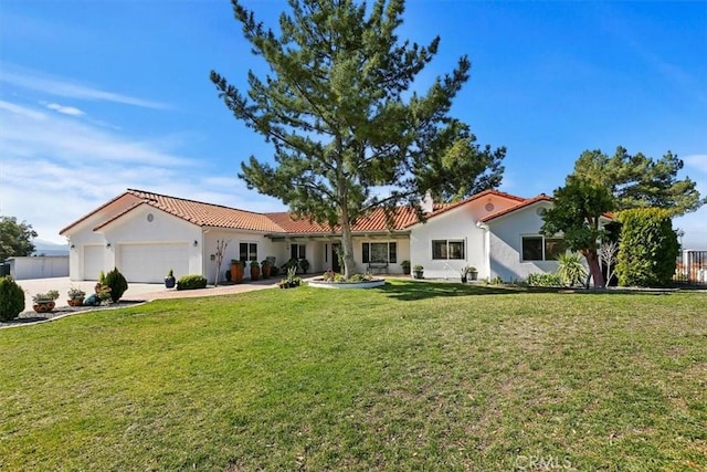 mediterranean / spanish-style home featuring a garage and a front lawn