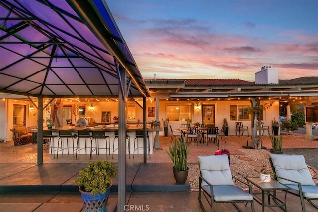 patio terrace at dusk featuring a bar