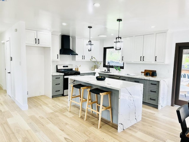 kitchen with stainless steel electric range oven, pendant lighting, white cabinetry, a center island, and wall chimney range hood