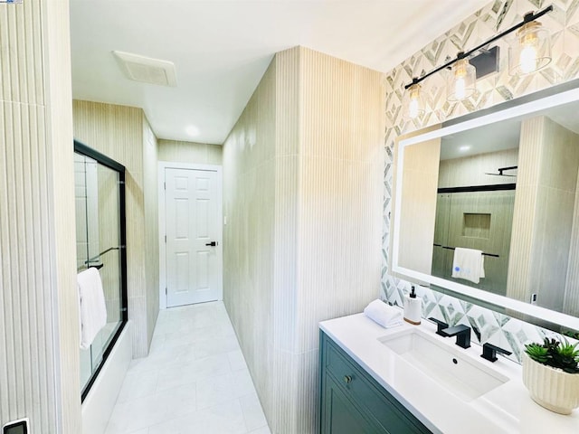 bathroom with walk in shower, vanity, tile patterned flooring, and tile walls