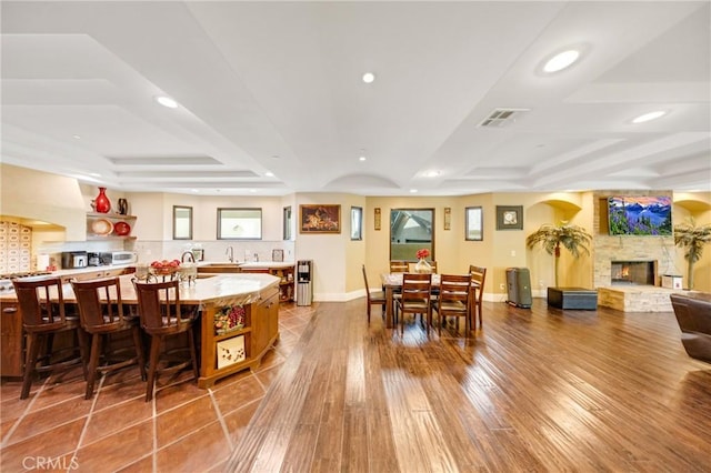 dining space featuring sink, a fireplace, a raised ceiling, and hardwood / wood-style floors