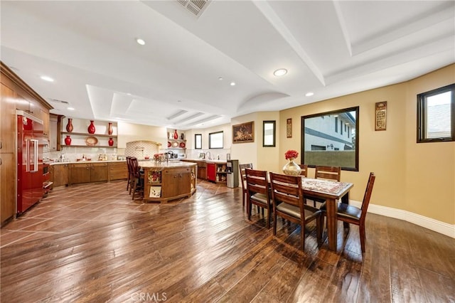 dining space with a raised ceiling, dark wood-type flooring, and sink