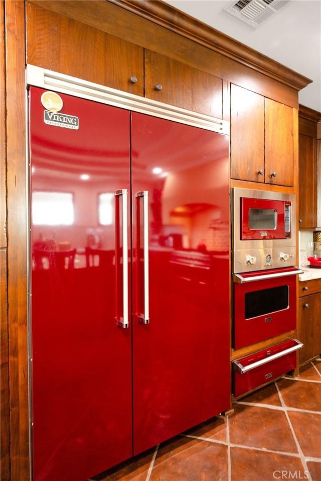 kitchen with built in appliances, decorative backsplash, and dark tile patterned floors