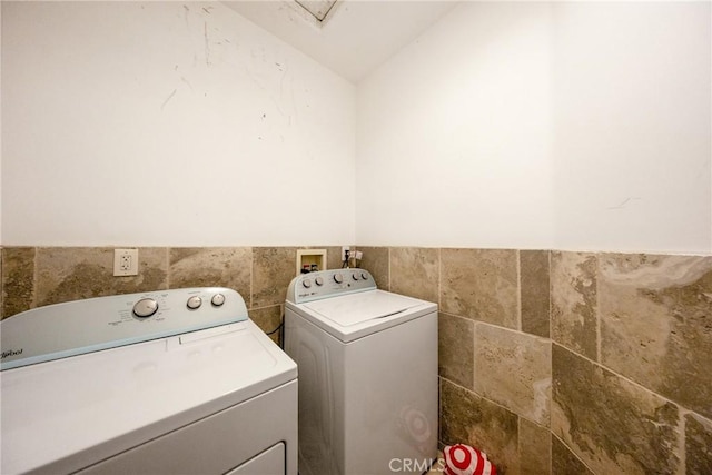 washroom with separate washer and dryer and tile walls