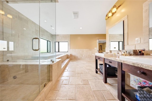 bathroom featuring tile walls, vanity, and plus walk in shower