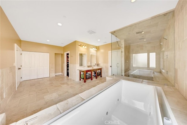 bathroom featuring vanity, plus walk in shower, and tile walls