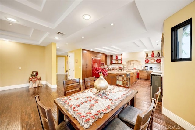 dining area with a raised ceiling, sink, and hardwood / wood-style floors