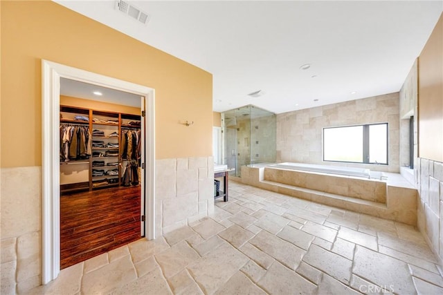 bathroom featuring independent shower and bath and tile walls