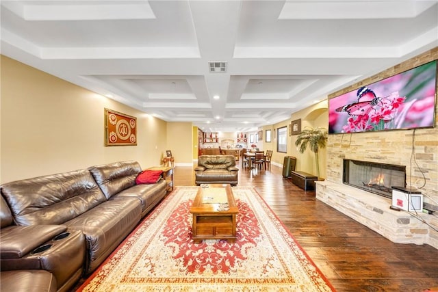 living room with coffered ceiling, hardwood / wood-style floors, and a stone fireplace