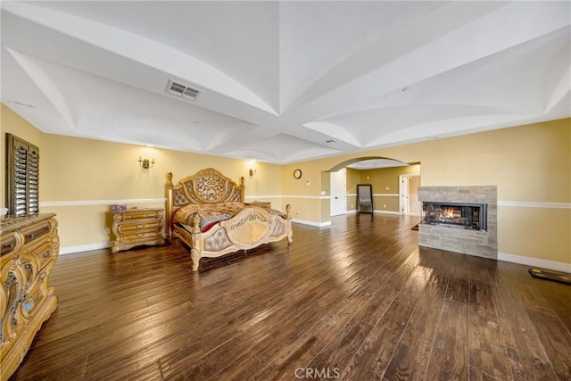 bedroom featuring a multi sided fireplace and dark hardwood / wood-style flooring