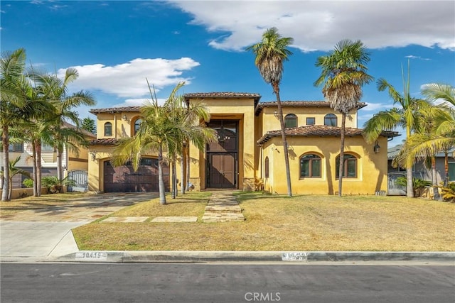 mediterranean / spanish house with a garage and a front lawn