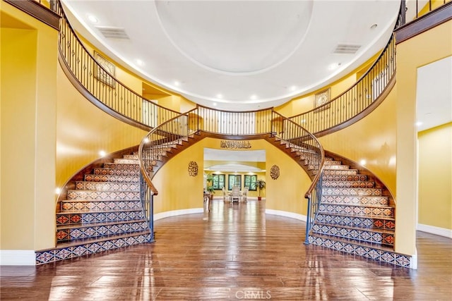 staircase featuring hardwood / wood-style floors and a high ceiling