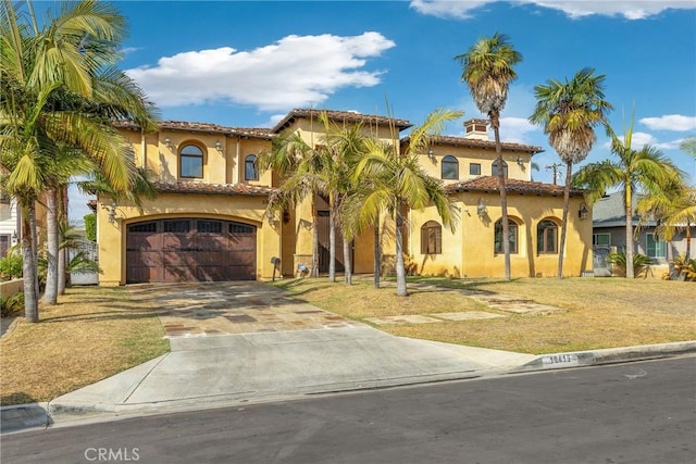 mediterranean / spanish-style house featuring a garage and a front yard