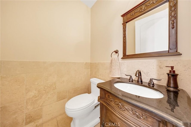 bathroom featuring vanity, toilet, and tile walls