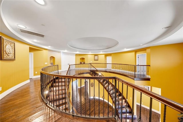 corridor with wood-type flooring and a tray ceiling