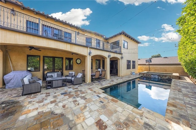 back of house with ceiling fan, an outdoor hangout area, a patio, and a balcony