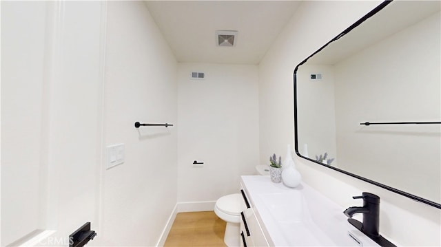 bathroom featuring wood-type flooring, toilet, and vanity