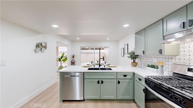 kitchen with sink, kitchen peninsula, green cabinets, stainless steel appliances, and decorative backsplash