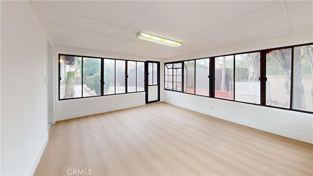 unfurnished room with plenty of natural light, a paneled ceiling, and light hardwood / wood-style floors