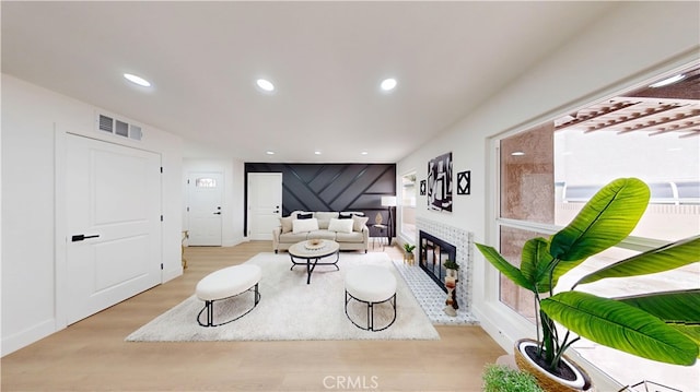 living room featuring a tiled fireplace and light wood-type flooring