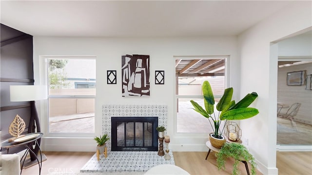 living area with a tile fireplace and light hardwood / wood-style floors