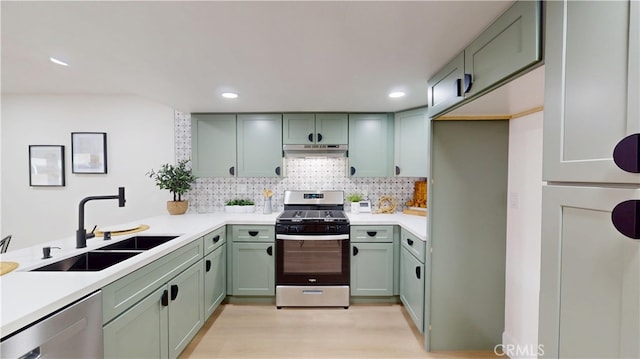 kitchen with tasteful backsplash, sink, green cabinets, light hardwood / wood-style floors, and stainless steel appliances