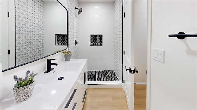 bathroom with tiled shower and vanity