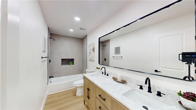 full bathroom featuring tiled shower / bath, hardwood / wood-style floors, vanity, and toilet