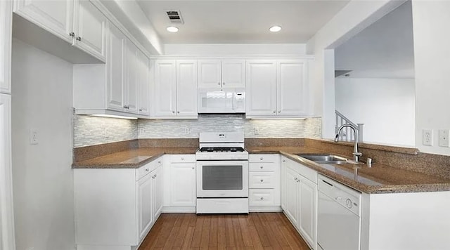 kitchen featuring white cabinetry, white appliances, kitchen peninsula, and dark stone countertops