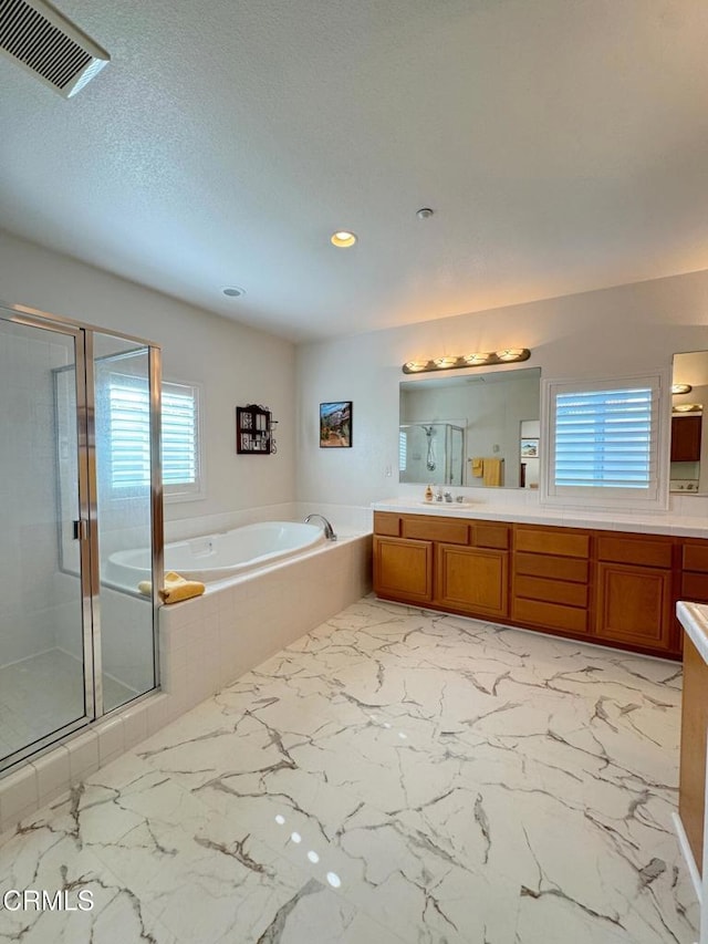 bathroom featuring independent shower and bath, vanity, and a textured ceiling