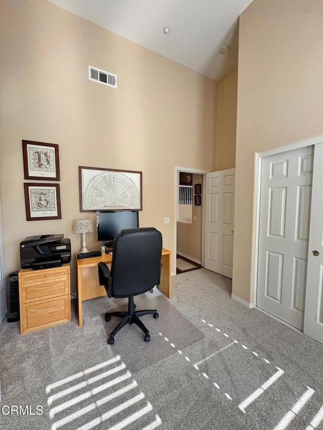 carpeted office space featuring a towering ceiling