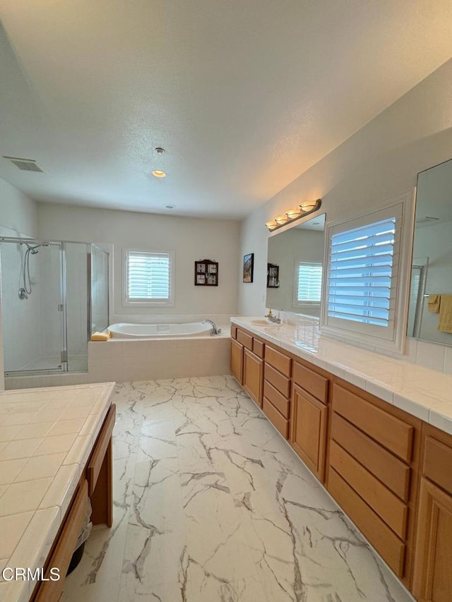 bathroom featuring shower with separate bathtub, vanity, and a textured ceiling