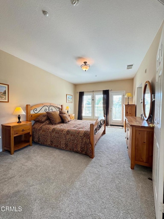 carpeted bedroom with access to outside and a textured ceiling