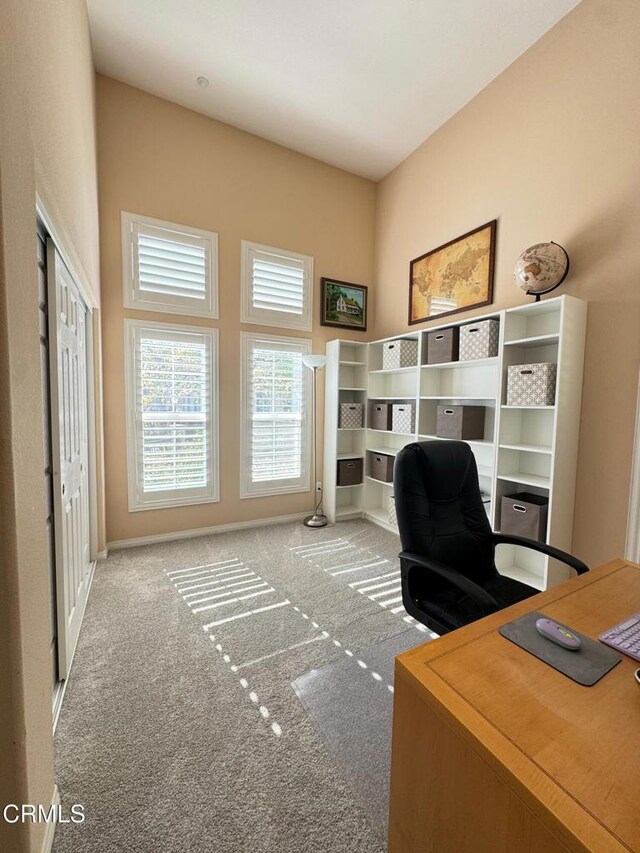 carpeted office space featuring a towering ceiling