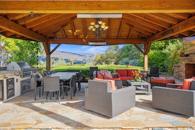 view of patio / terrace featuring an outdoor kitchen, a grill, an outdoor living space with a fireplace, a gazebo, and a mountain view