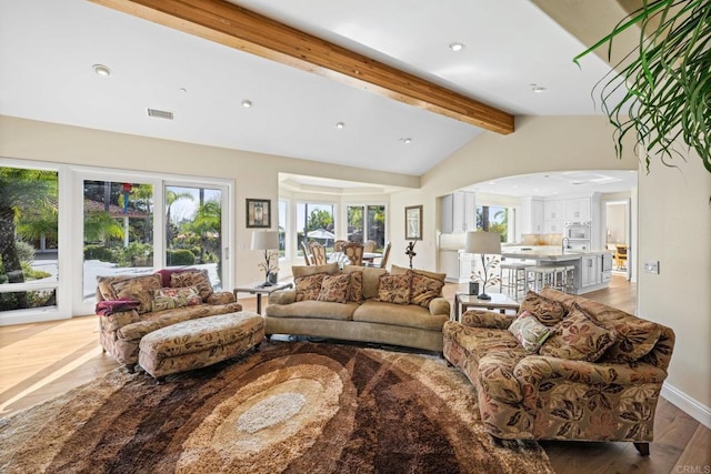 living room featuring vaulted ceiling with beams and light hardwood / wood-style floors