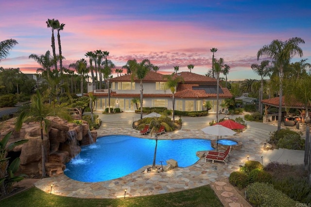 pool at dusk with a patio area