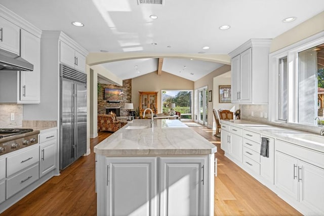 kitchen with white cabinetry, stainless steel appliances, sink, and a center island with sink