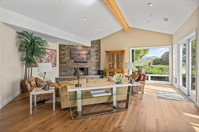 living room with vaulted ceiling with beams, a fireplace, and light wood-type flooring