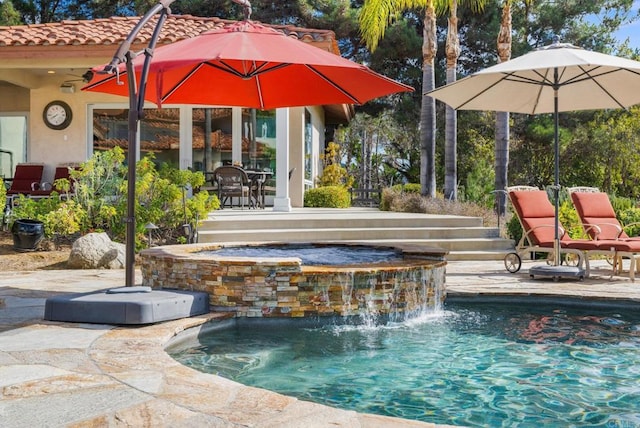 view of pool featuring a patio, pool water feature, and an in ground hot tub