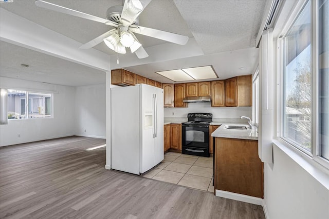 kitchen featuring black electric range oven, white refrigerator with ice dispenser, sink, and a healthy amount of sunlight